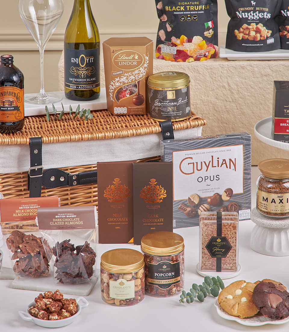 Luxury chocolate and tea gift hamper in wicker basket with Lindt chocolates, Charlotte bars, gourmet snacks, and premium