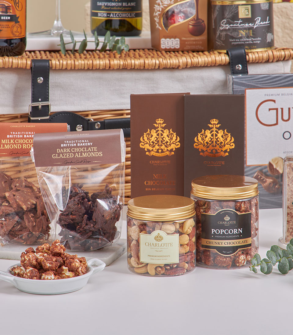 Luxury chocolate and tea hamper with gourmet treats, dark and milk chocolate bars, baked goods, and nuts in gold-accented