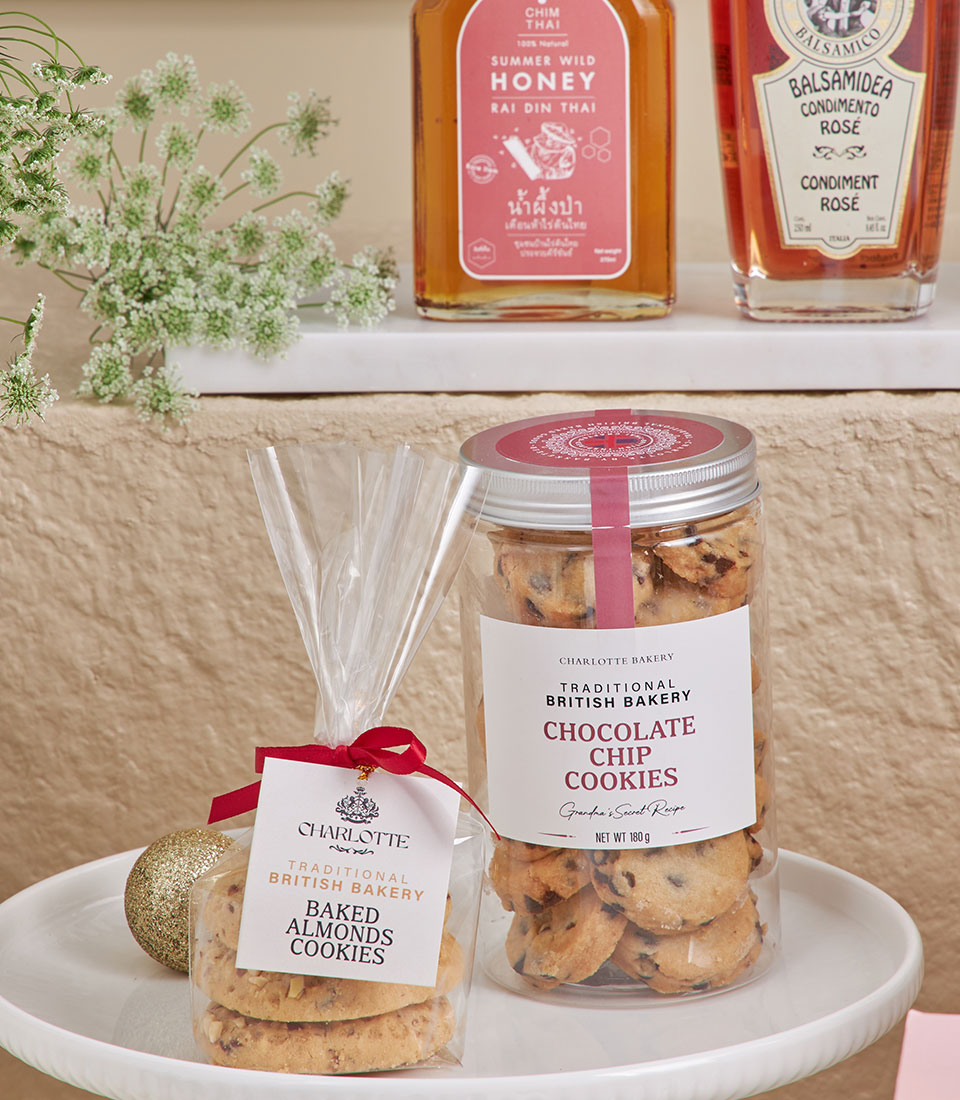Luxury gourmet gift set with almond cookies, chocolate chip cookies, wild honey, and balsamic condimento on tiered white