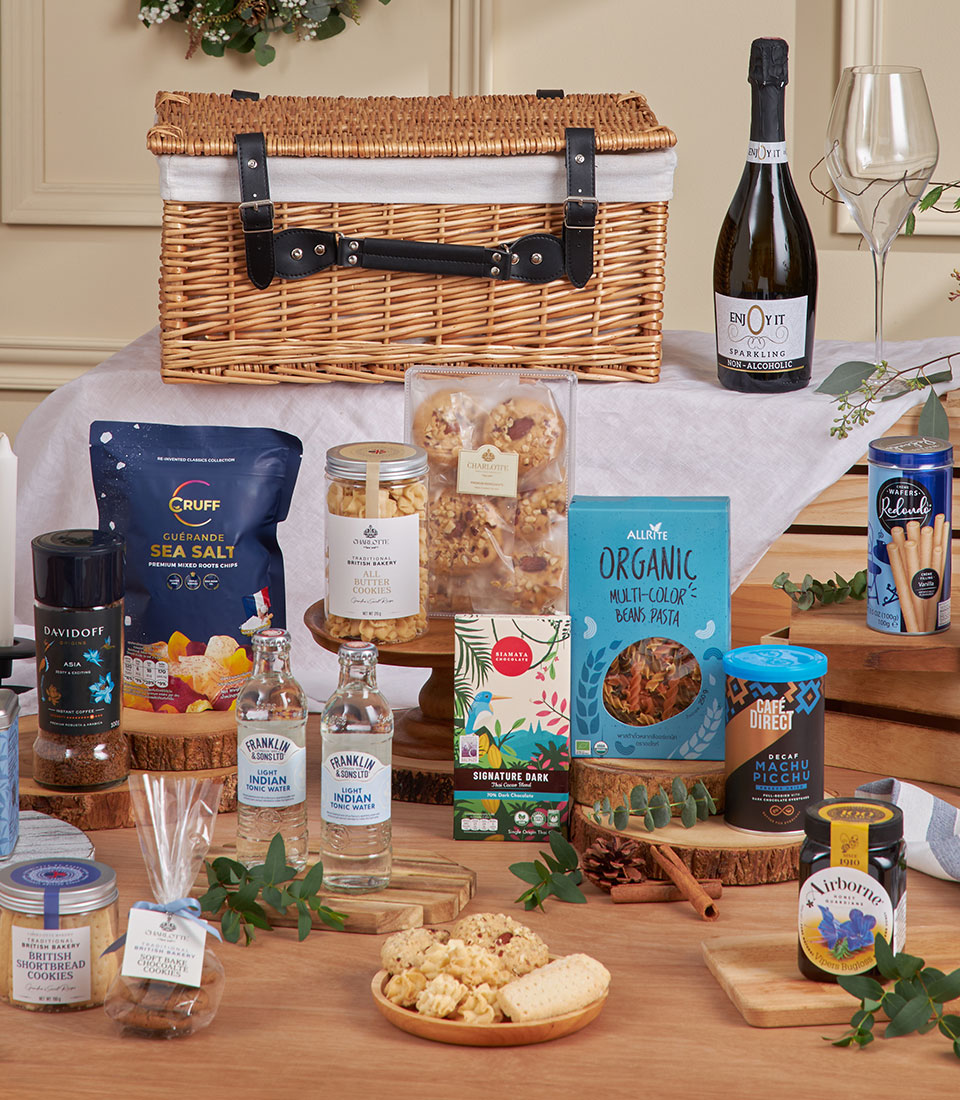 Luxury gourmet gift hamper with sparkling beverages, artisan snacks, and manuka honey in wicker basket