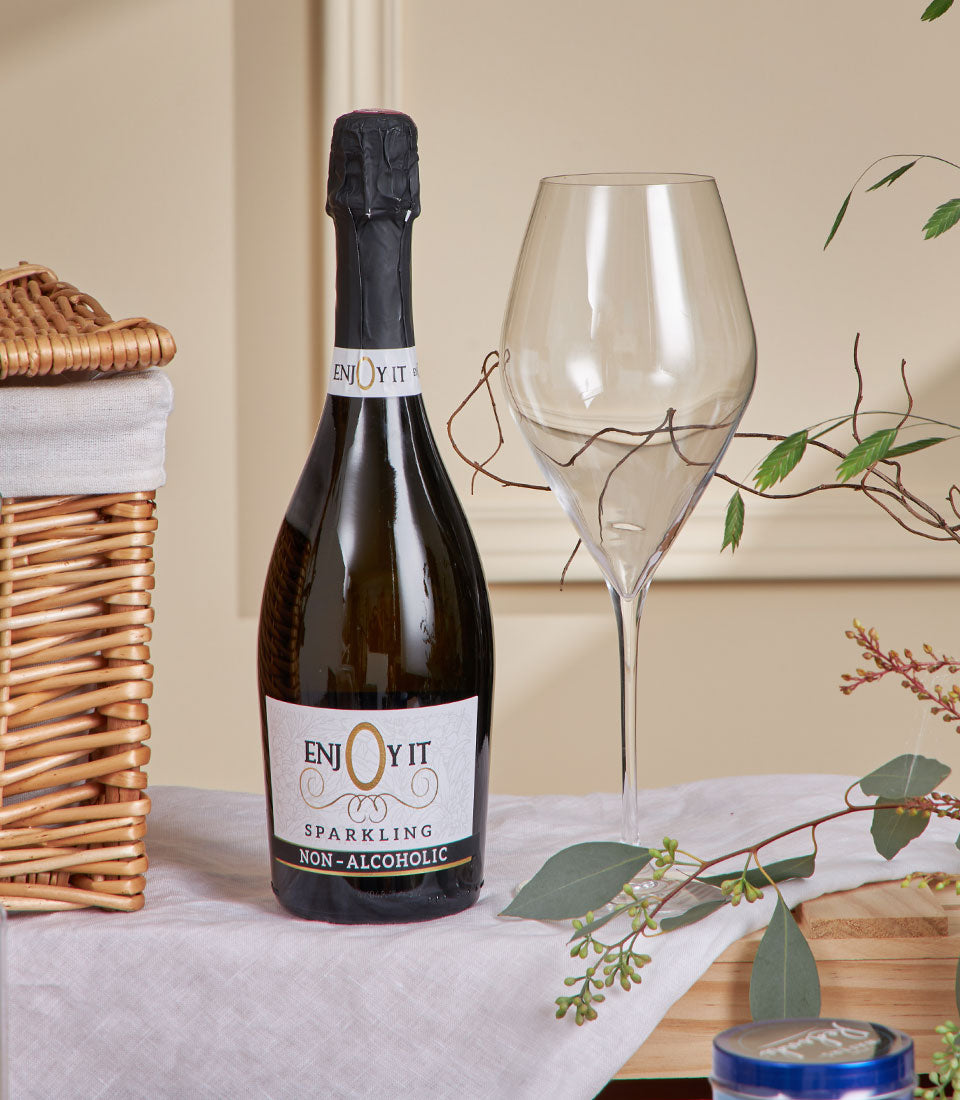 Luxury New Year gift basket with non-alcoholic sparkling beverage, woven wicker hamper, and fresh eucalyptus greenery