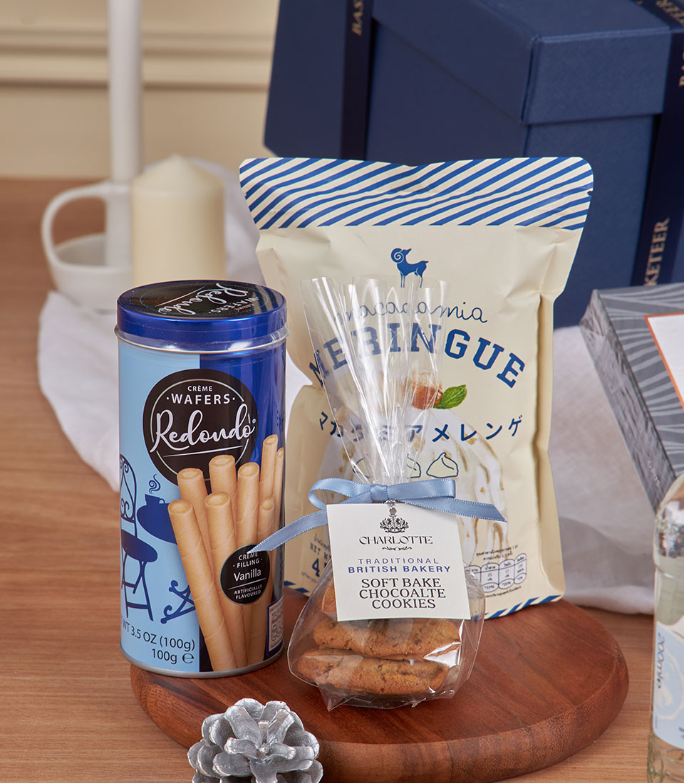 Premium gourmet gift basket with wafers, meringue cookies, and chocolate treats on wooden board for New Year