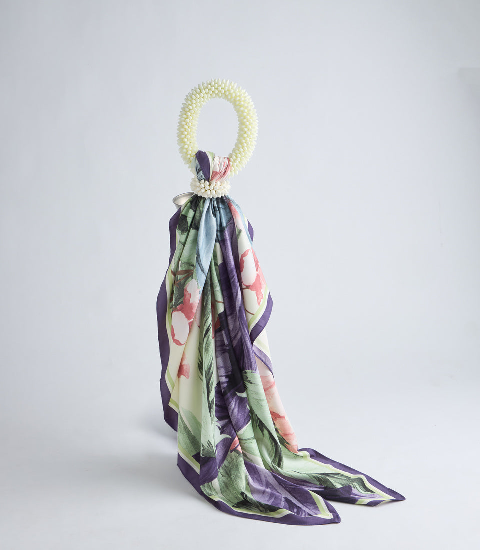 Cream pearl beaded loop handle with floral silk scarf in purple, pink, and green attached at base, trailing fabric below.