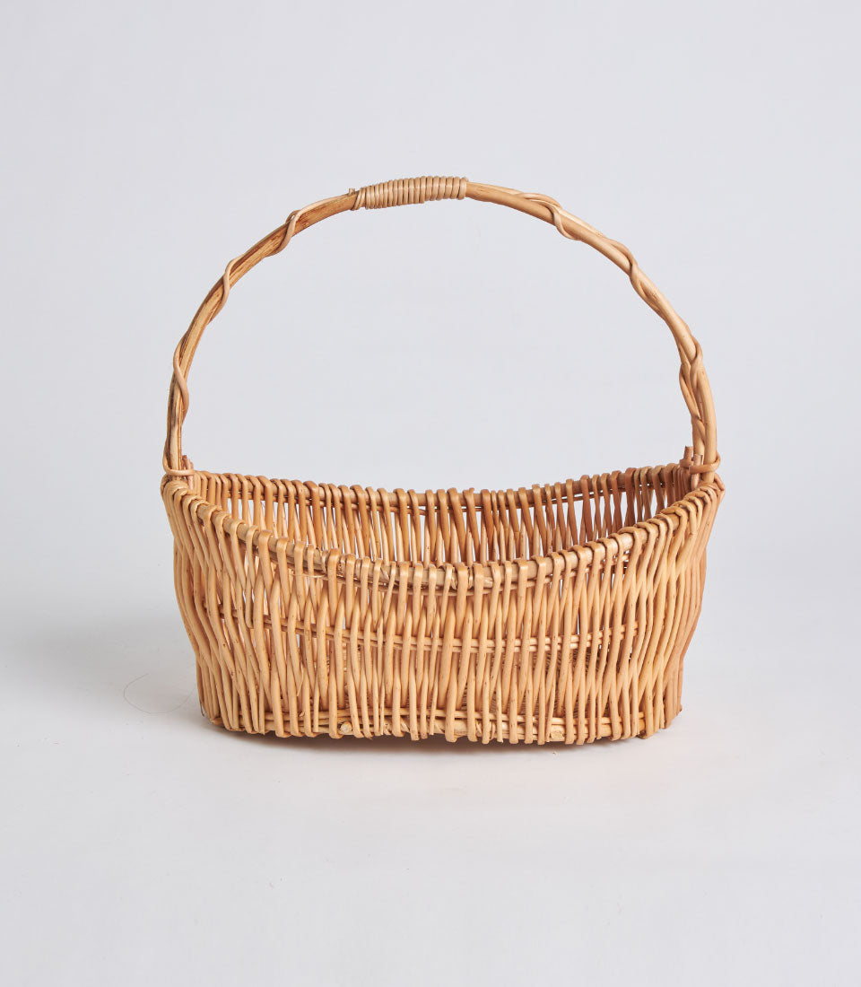 Handwoven light brown wicker basket with single arched handle for gift hampers and artisan presentations