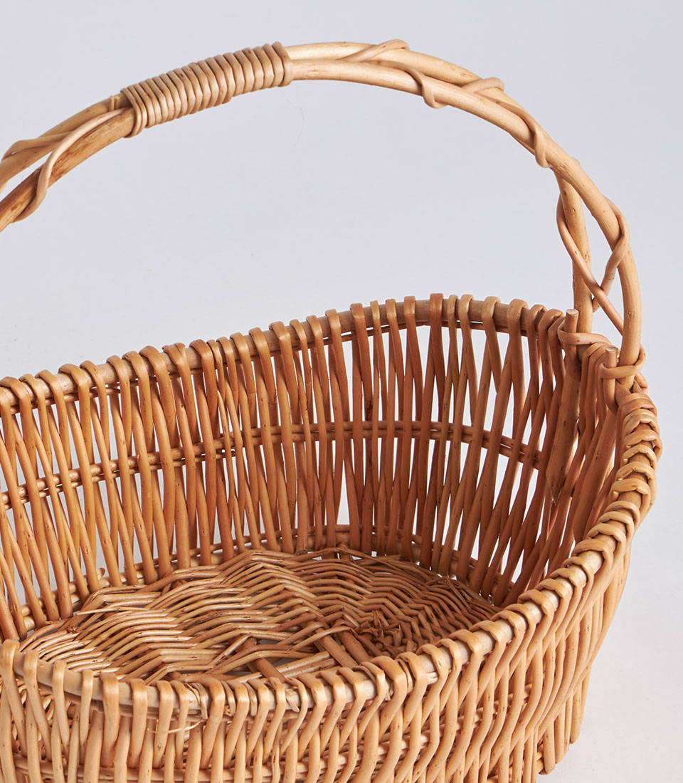 Natural wicker oval basket with single arched handle and zigzag weave detail
