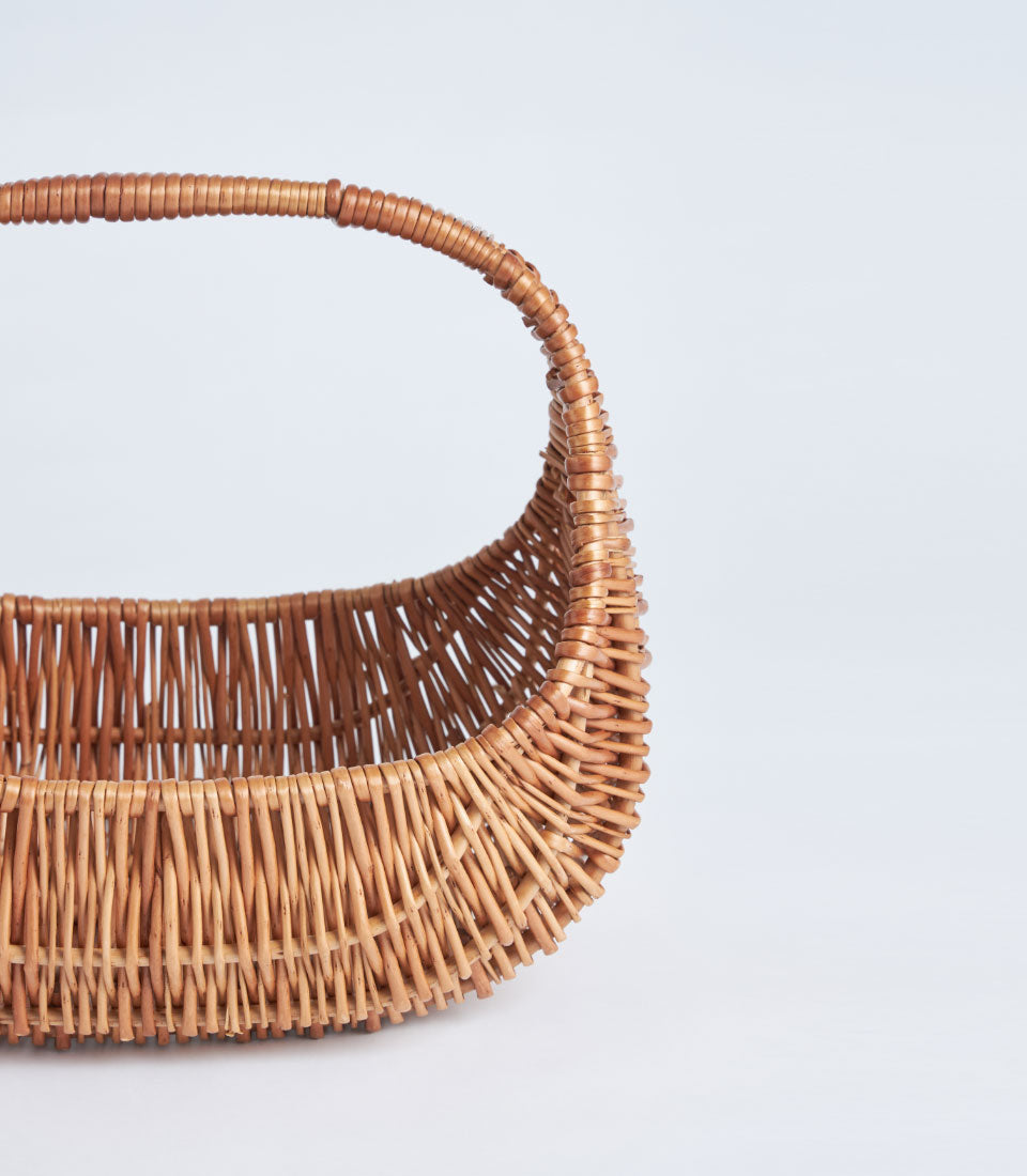Light brown handwoven wicker basket with curved handle, artisan gift packaging