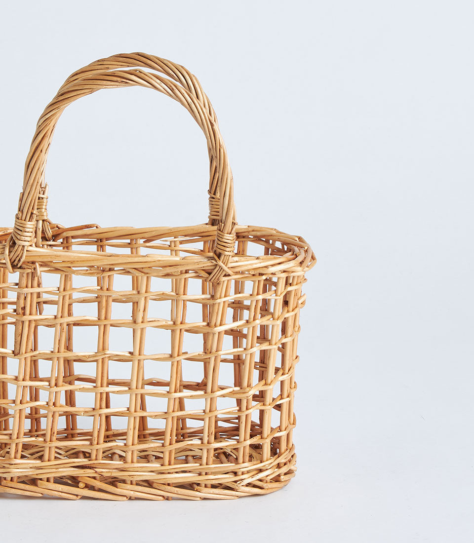 Light brown handwoven open-weave wicker basket with arched handle