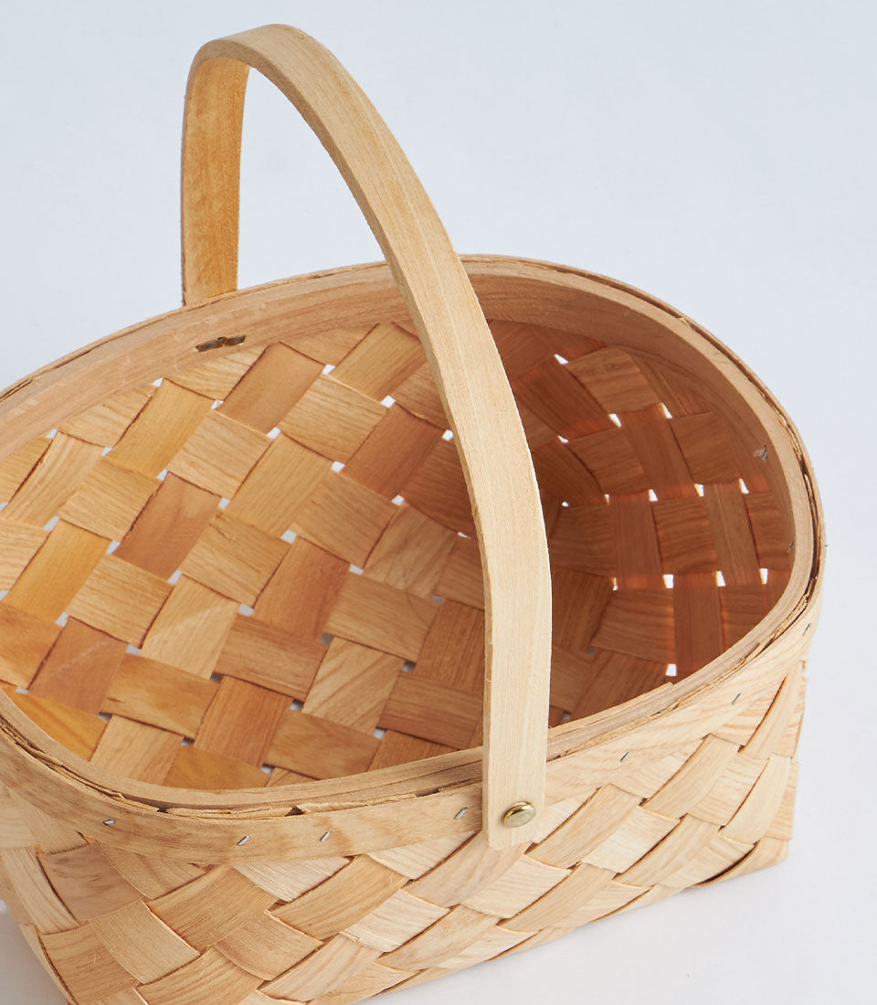 Natural woven bamboo oval basket with arched handle, light wood tone
