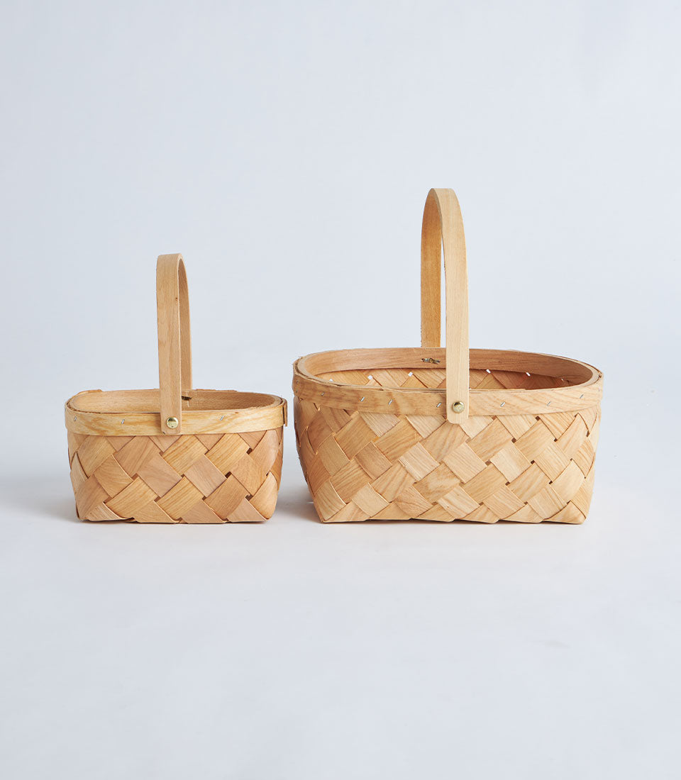 Natural woven bamboo oval baskets with handles in light wood tone, displayed in two sizes