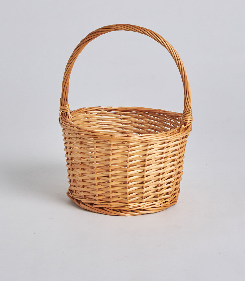 Handwoven light brown rattan storage basket with arched handle, artisan crafted