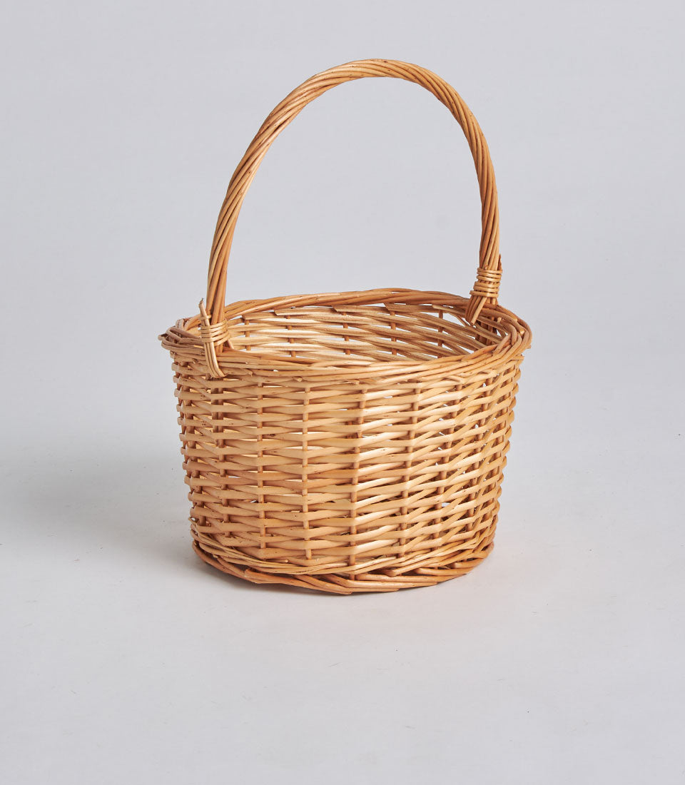 Handwoven light tan rattan storage basket with arched handle for gifting