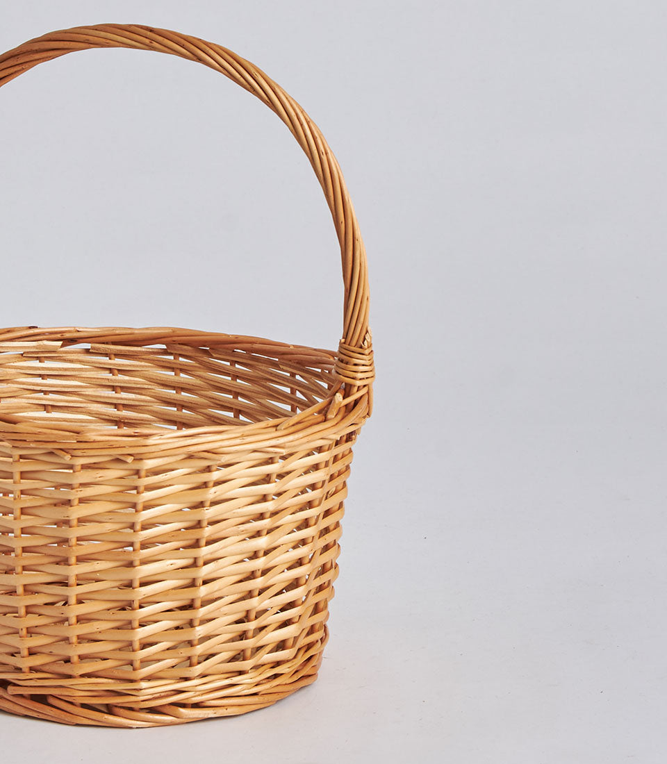 Light brown handwoven rectangular storage basket with arched wicker handle, perfect for luxury gift giving