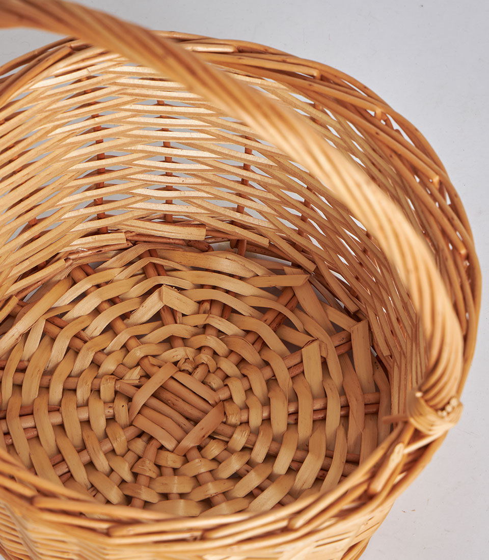 Light brown handwoven rattan storage basket with arched handle and traditional wicker pattern