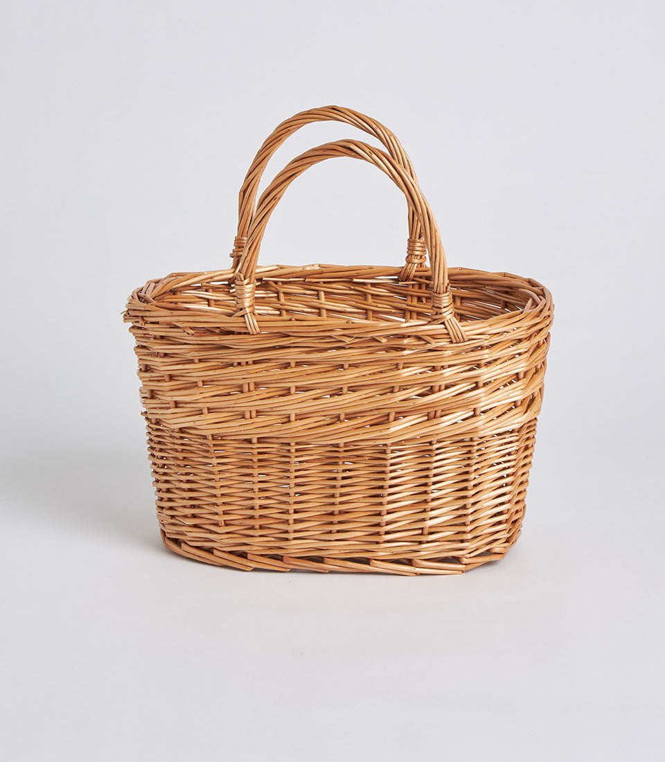 Handwoven oval wicker basket with dual handles in natural light brown rattan