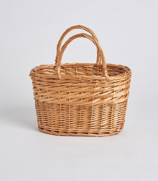 Handwoven oval wicker basket with dual handles in natural light brown rattan