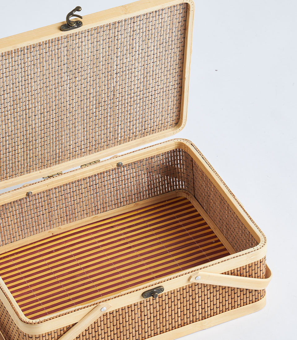 Light woven wicker rectangular gift basket with striped linen interior and bamboo handles