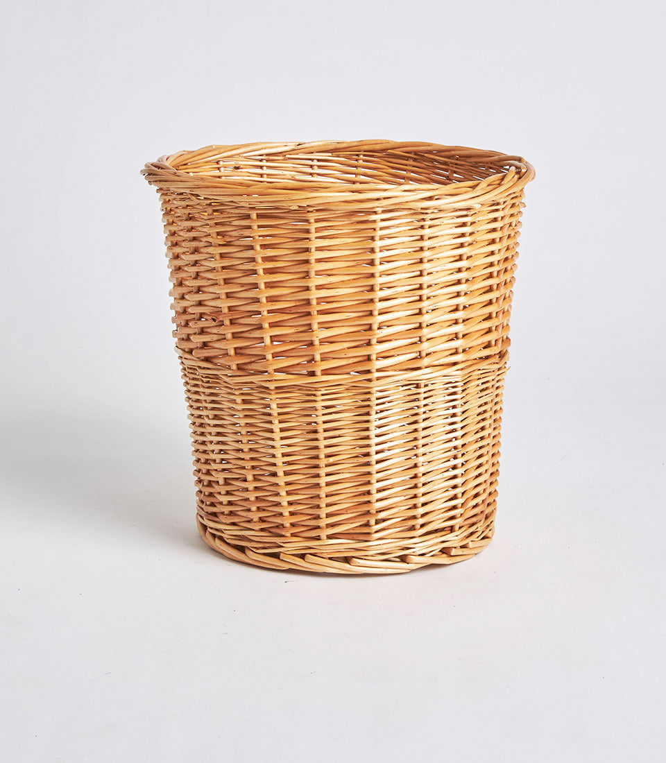 Tall cylindrical handwoven wicker storage basket in natural light brown with tight artisan weaving