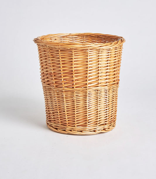 Tall cylindrical handwoven wicker storage basket in natural light brown with tight artisan weaving