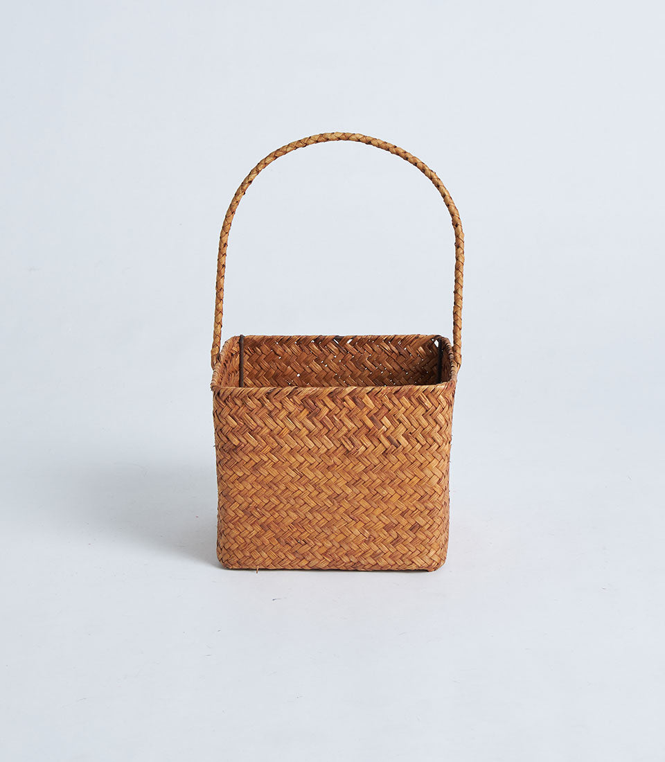 Natural brown woven rattan basket with braided handle for gifting and storage