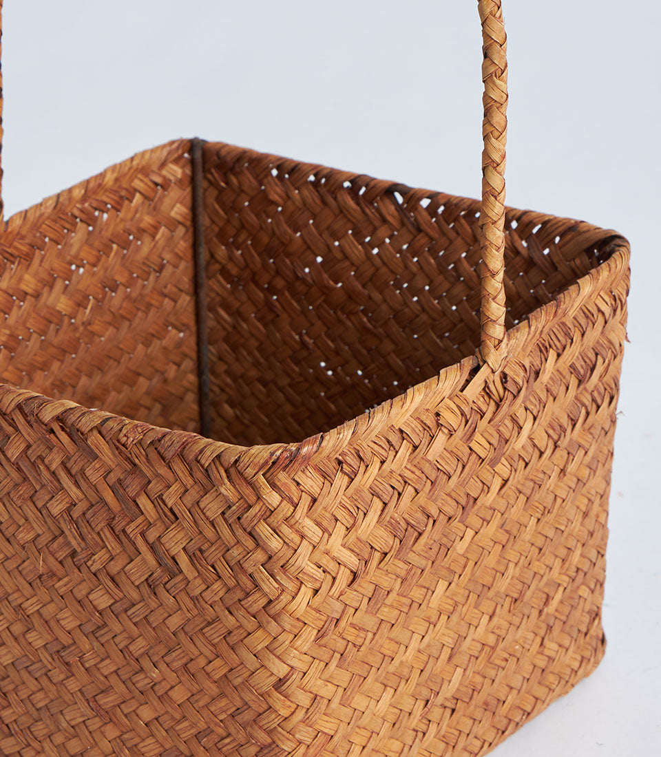 Hand-woven natural brown fiber basket with braided handles, artisan gift container