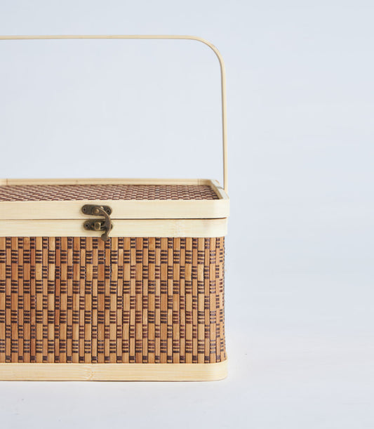Light brown woven bamboo picnic basket with brass clasp and curved handle