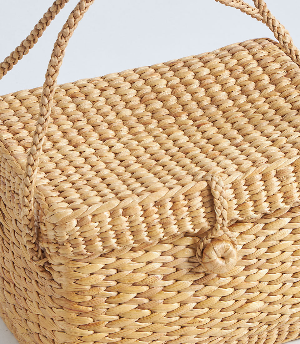 Handwoven natural straw basket with braided handles and button closure