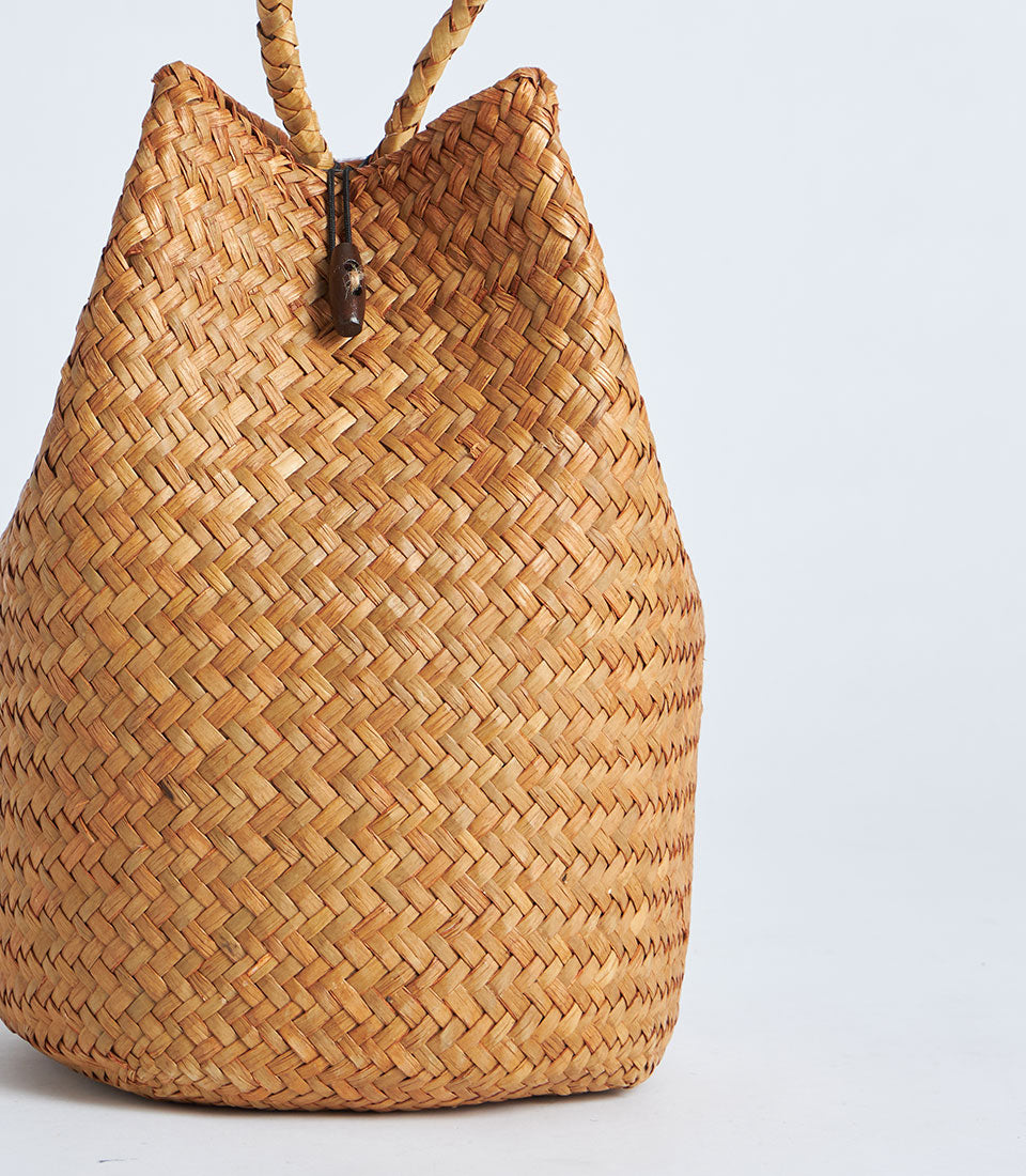 Natural straw gift basket with rope handle and red tassel, woven light brown bucket-style bag