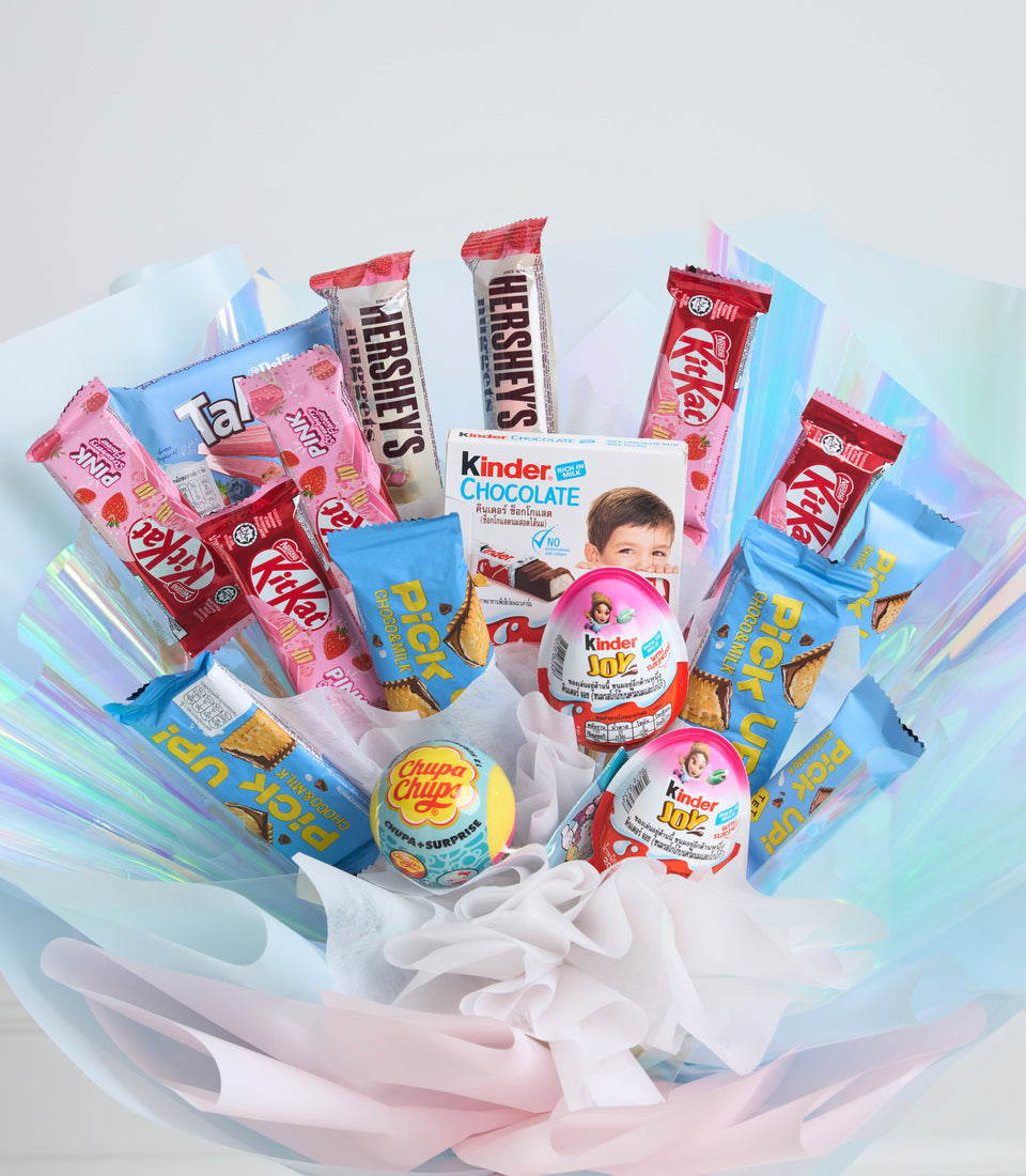 Colorful candy gift bouquet with Kit Kat, Kinder chocolate, Chupa Chups, and cookies arranged in blue and pink tissue wrapping.