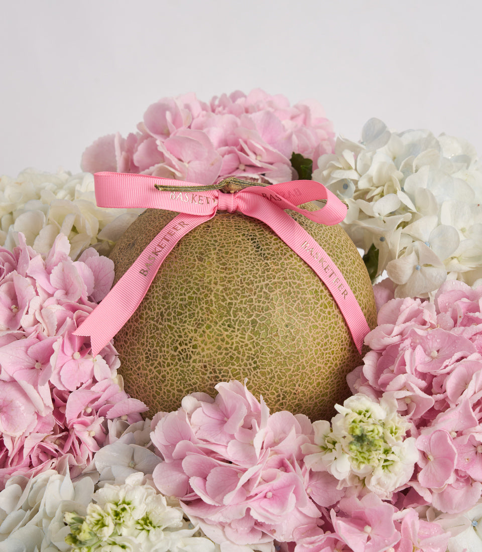 # Alt Text

Gold textured sphere with pink ribbon bow surrounded by pink and white hydrangeas and carnations in elegant floral arrangement.