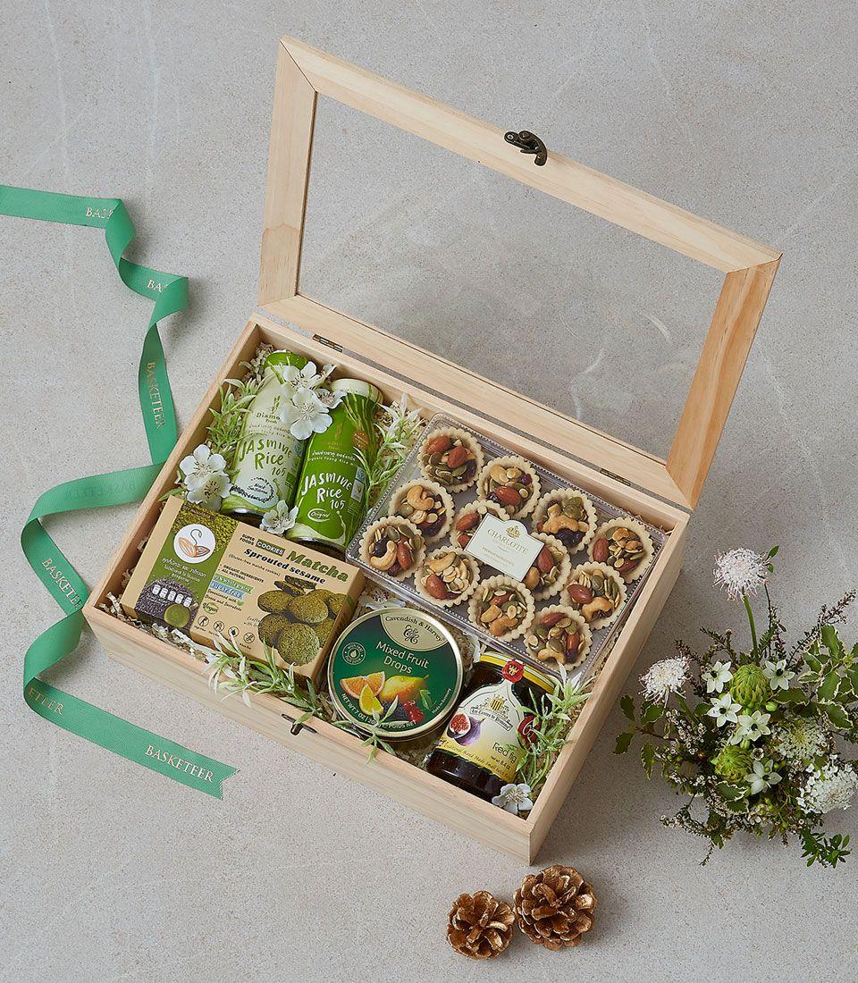 Premium wooden gift box with gourmet treats, matcha cookies, nut tarts, and fig jam on light green filler