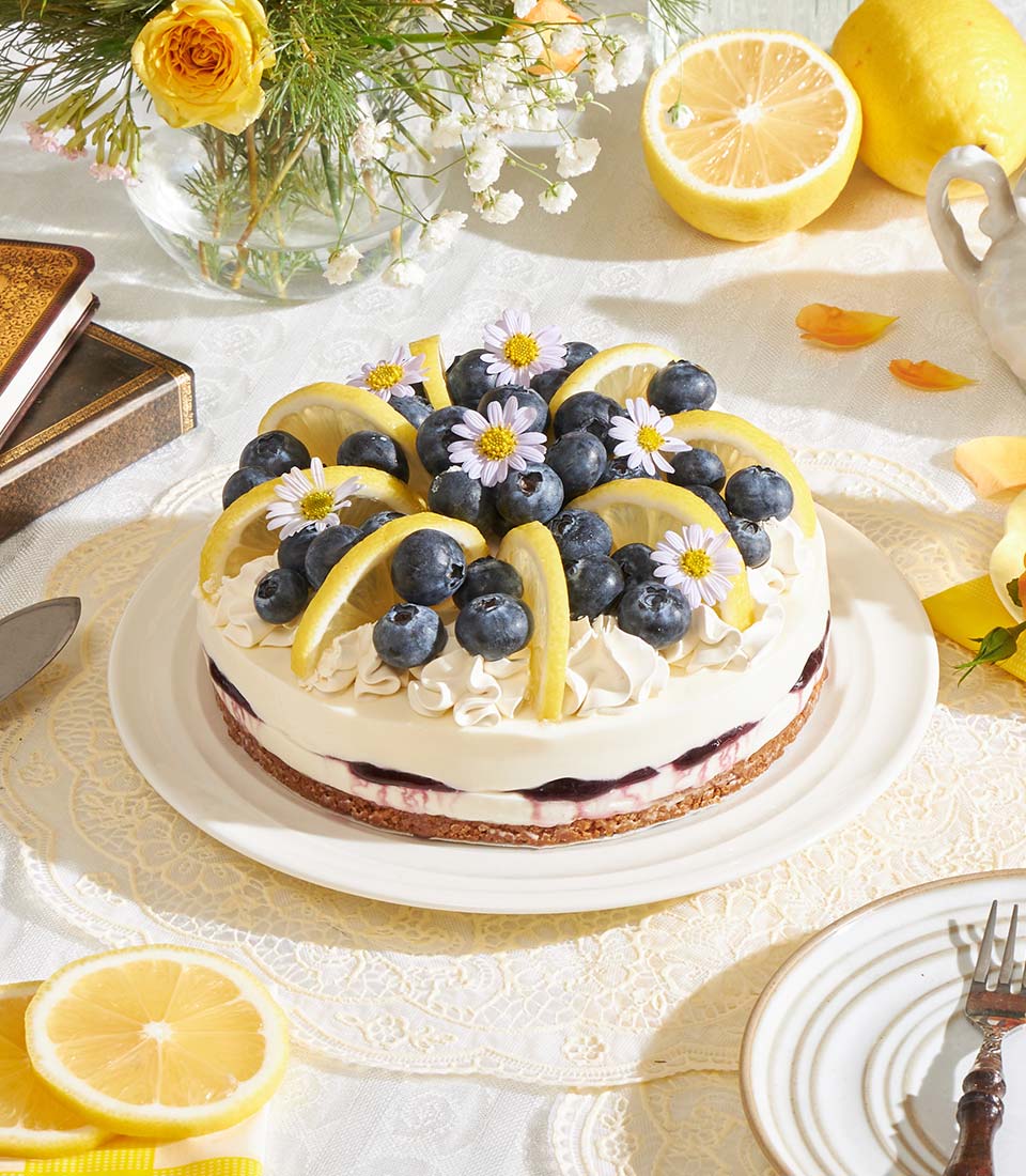 Lemon Blueberry Biscoff Cheesecake with fresh berries and edible flowers on white plate