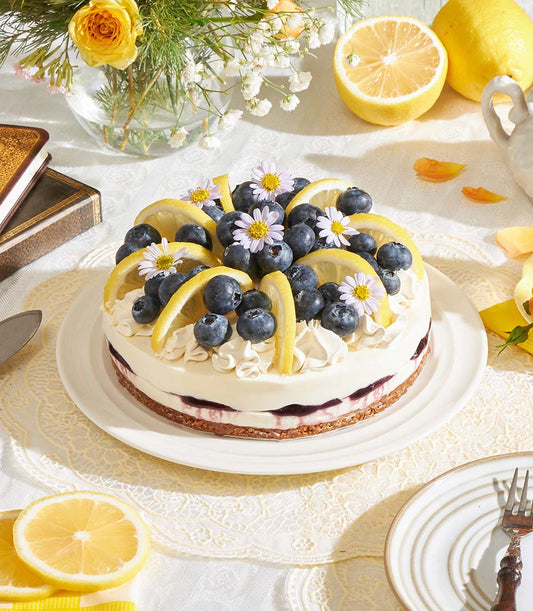 Lemon Blueberry Biscoff Cheesecake with fresh berries and edible flowers on white plate