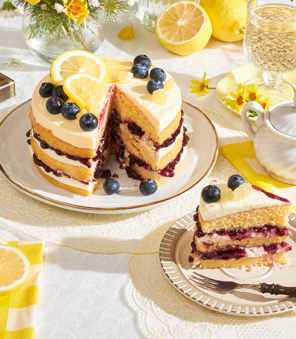 Lemon blueberry layer cake with cream cheese frosting, fresh berries and candied citrus garnish
