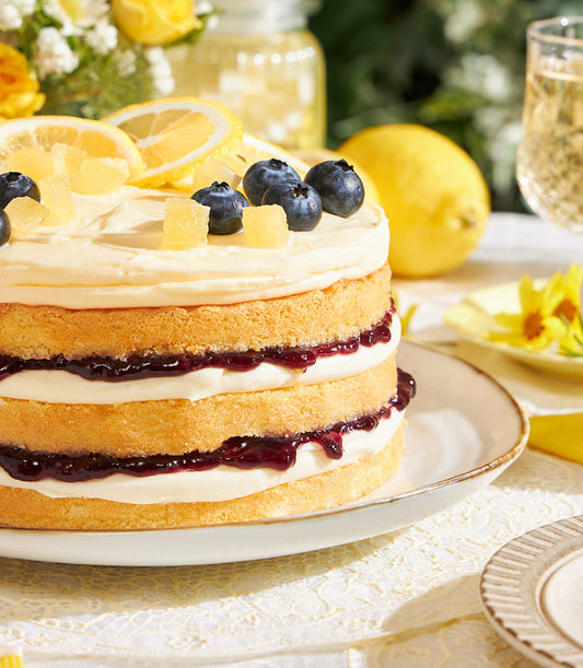 Three-layer lemon blueberry sponge cake with cream cheese frosting, candied lemon peel, and fresh berries