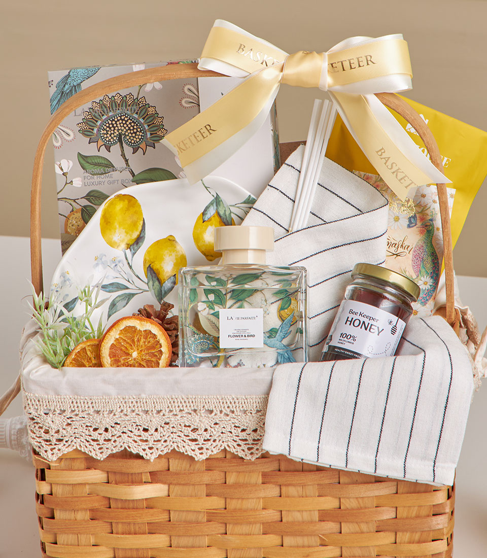 Woven wicker spa basket with lemon-patterned ceramic, honey jar, floral diffuser, and dried citrus wellness gifts