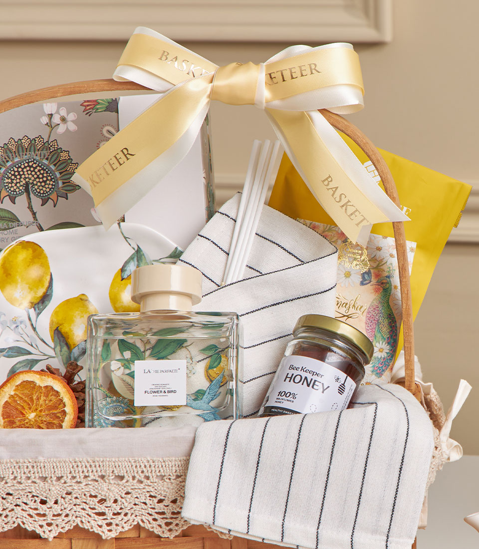 Lemon Grove home spa basket with honey, scented diffuser, striped towel, and botanical-print linens