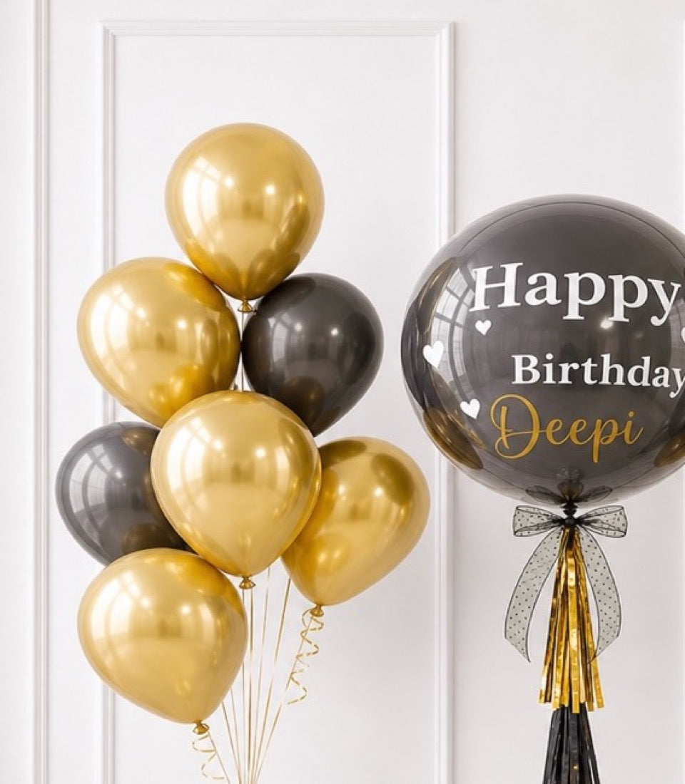 Gold and black metallic balloons with "Happy Birthday Deepi" personalized balloon featuring decorative ribbon bow.