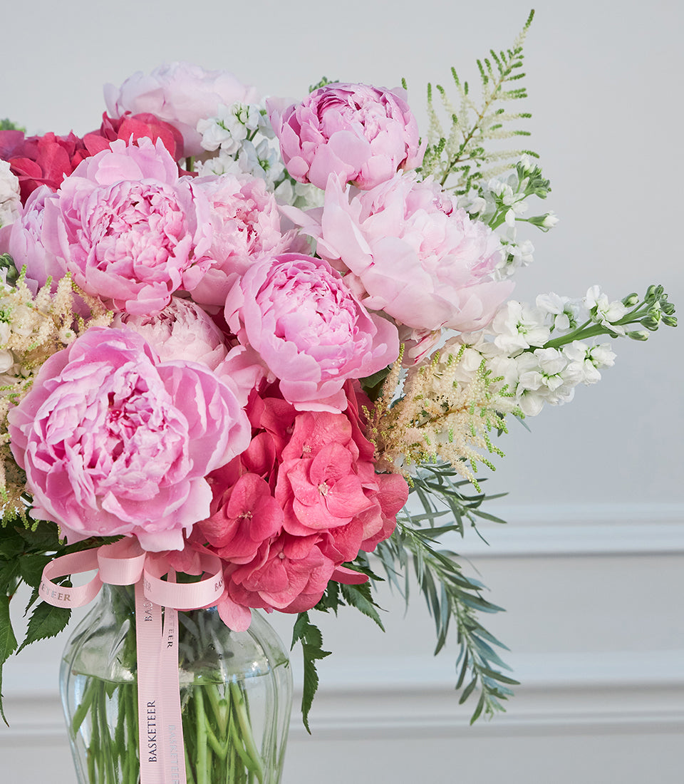 Elegant vase arrangement of lush pink peonies, vibrant fuchsia hydrangeas,