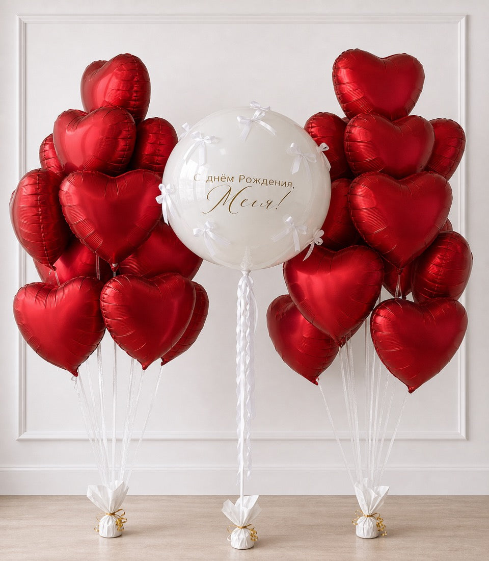Red heart-shaped foil balloons with white center balloon featuring Russian birthday text, white ribbons and gold weights.