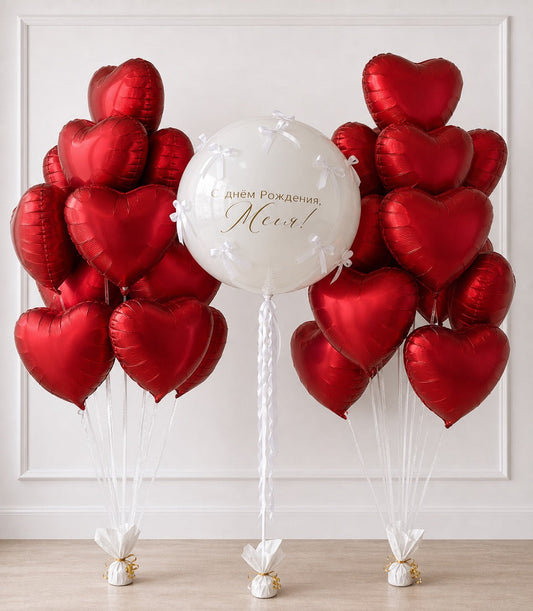 Red heart-shaped foil balloons with white center balloon featuring Russian birthday text, white ribbons and gold weights.