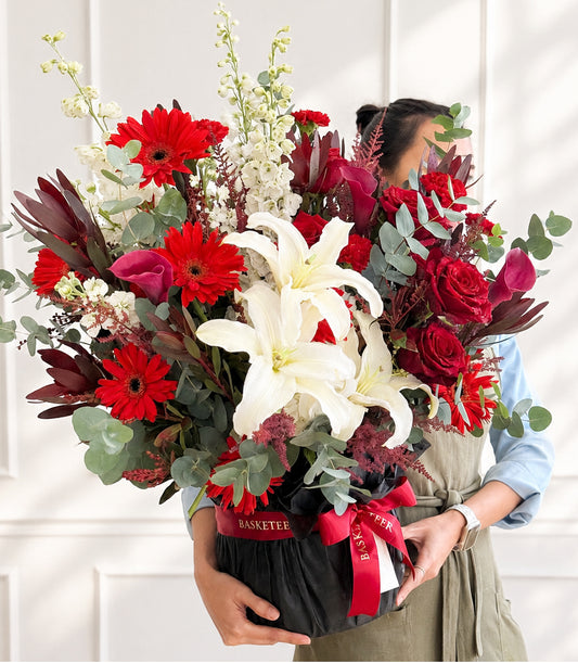 Luxurious Flowers by Basketeer arrangement featuring premium red roses, white lilies,
