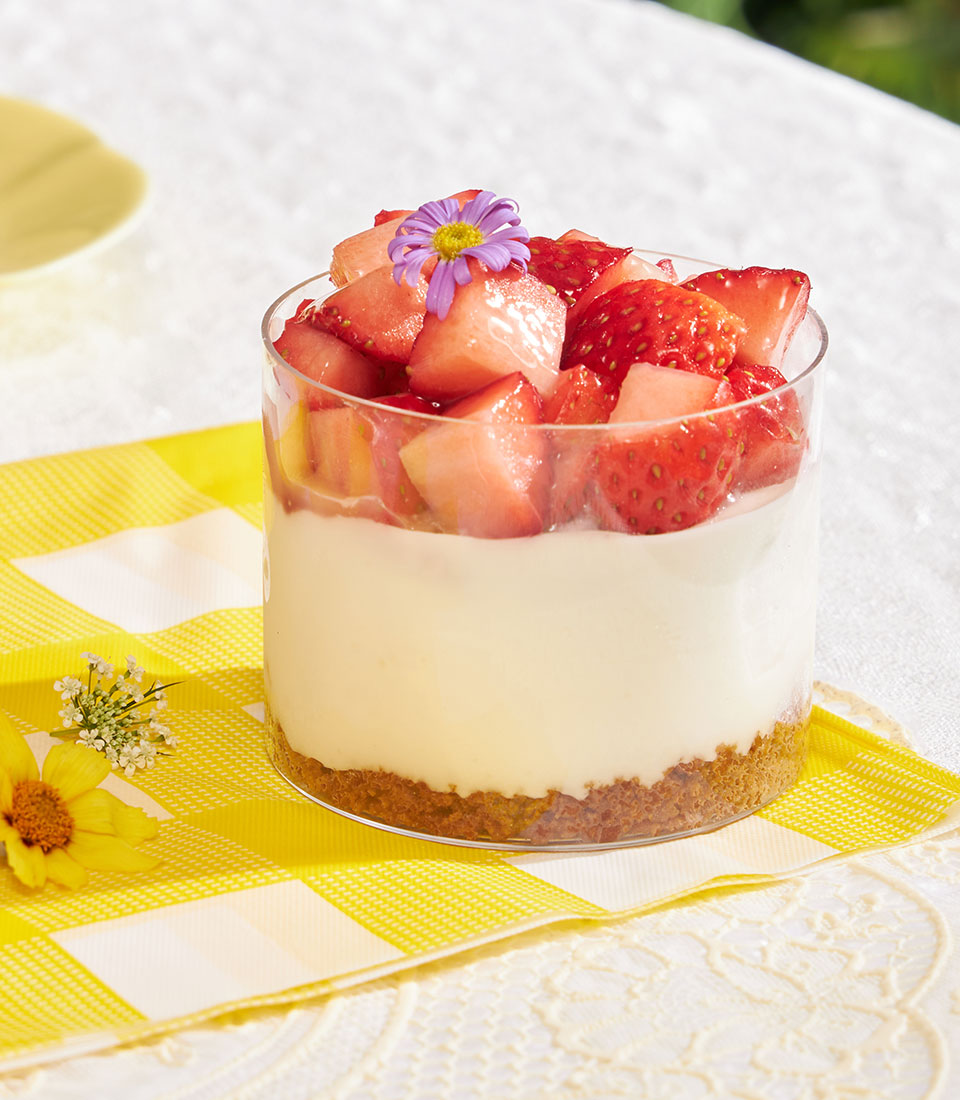 Mini cheesecake cup with Biscoff base, creamy filling, and fresh strawberry topping in clear glass
