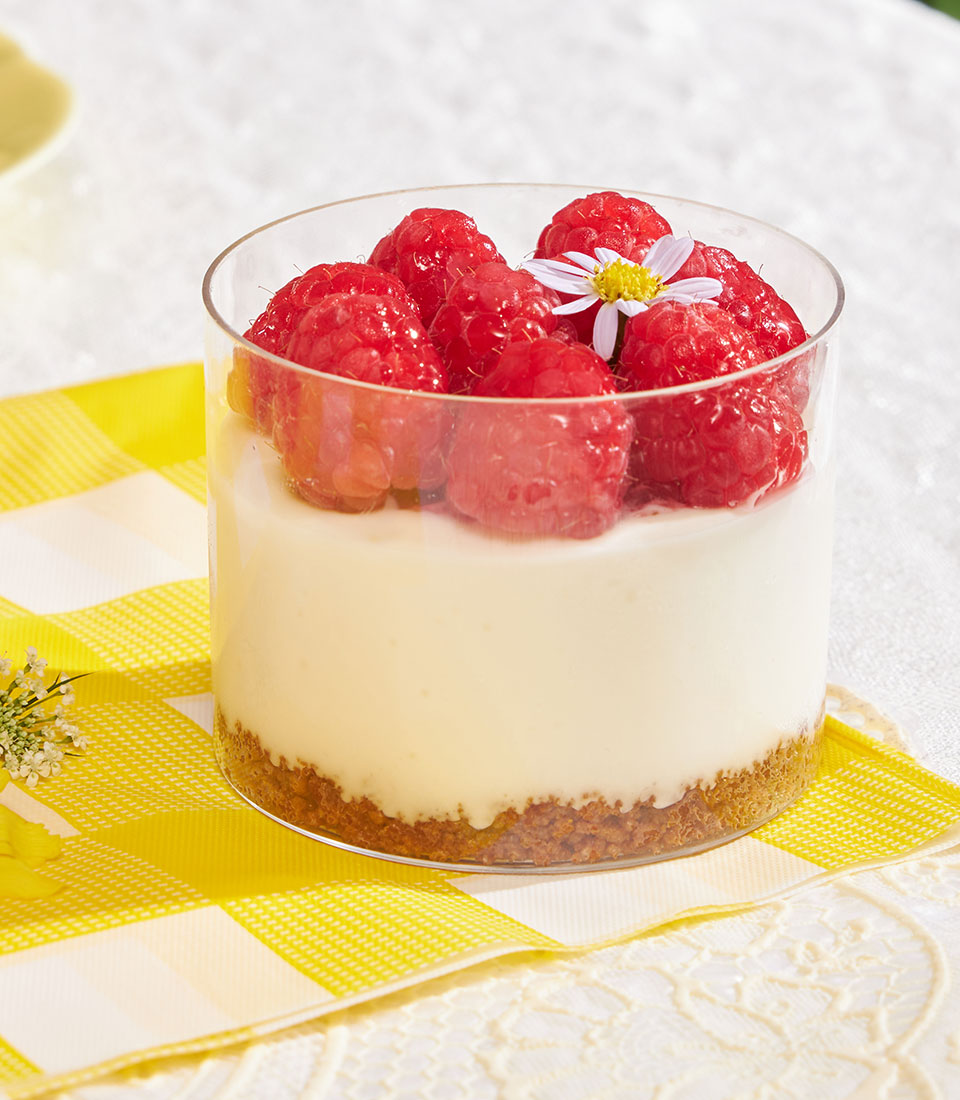 Mini cheesecake cup with Biscoff biscuit base, creamy filling, and fresh raspberries in clear glass