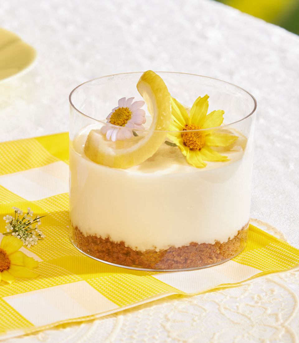 Mini cheesecake cup with Biscoff biscuit base, creamy filling, and fresh fruit garnish in clear glass