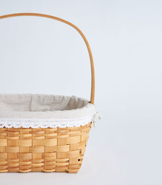 Luxurious handwoven rectangular wicker basket with a graceful handle and a delicate cream fabric