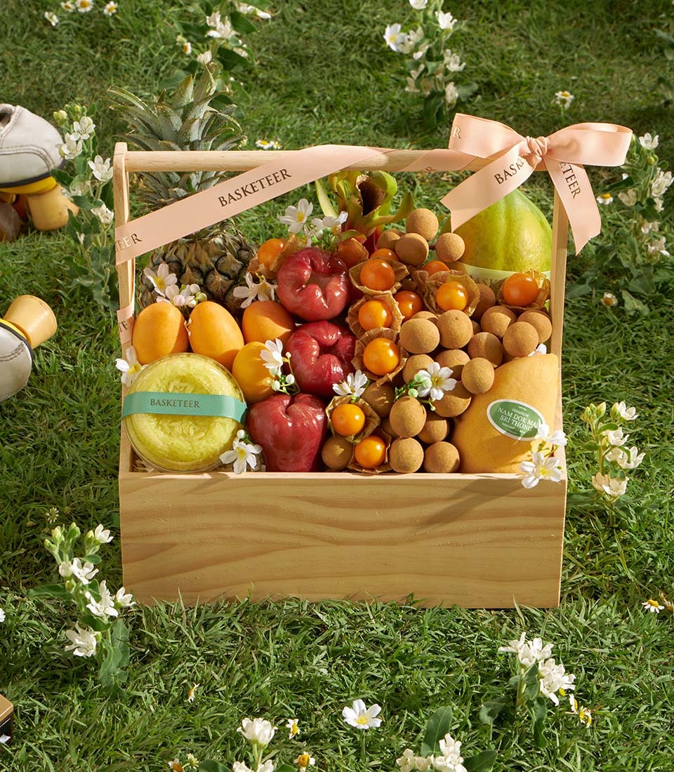 Premium Thai tropical fruit basket with pineapple, mangoes, rose apples, longans, and fresh flowers