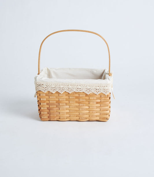 Light brown handwoven wicker gift basket with wooden handle and cream lace-trimmed fabric liner