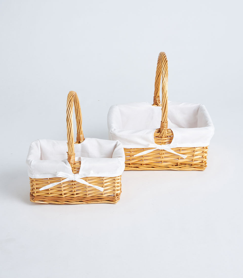 Two elegant Basketeer handwoven wicker baskets with white fabric lining and delicate