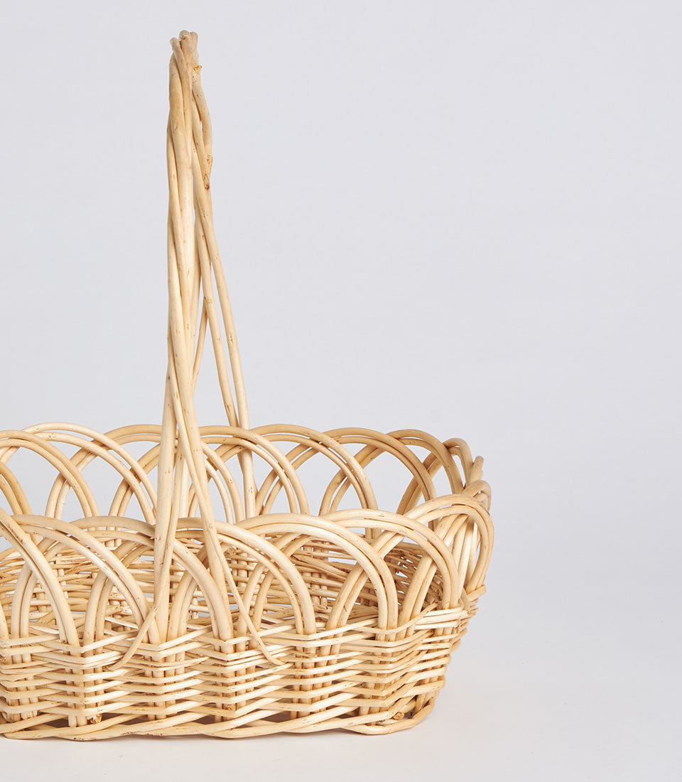 Natural wicker oval basket with tall arched handle, handwoven rattan in light neutral tone
