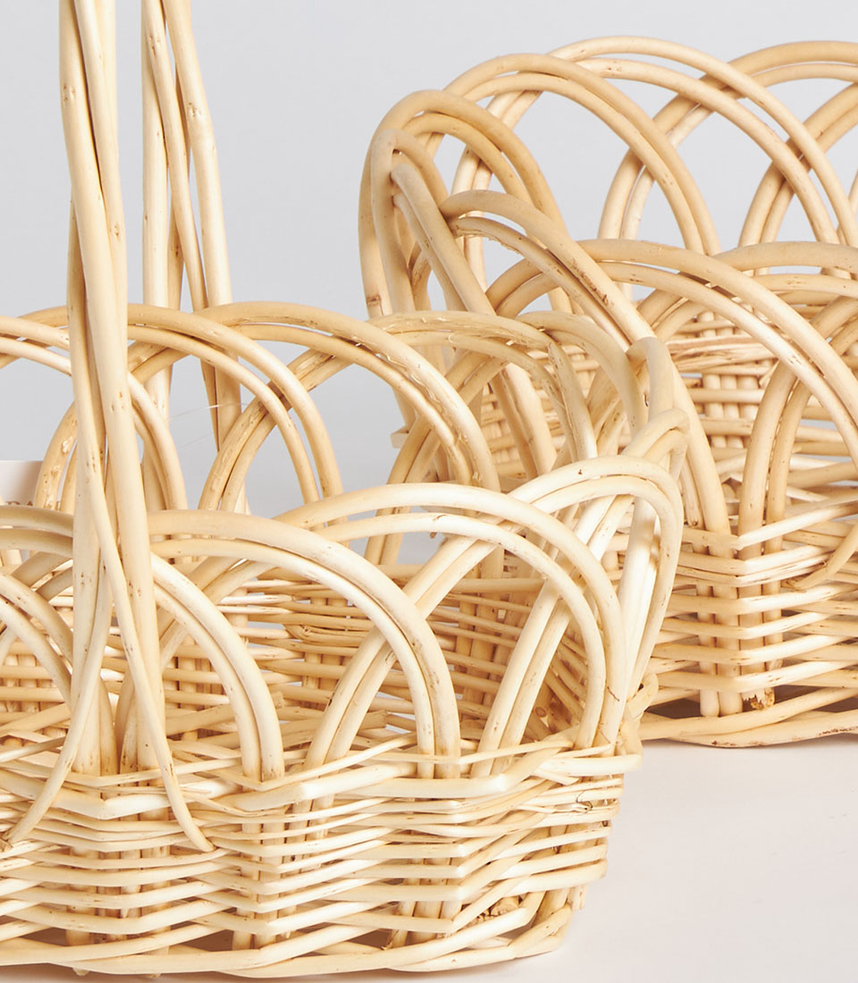 Handwoven light natural wicker baskets with tall arched handles and open-weave decorative sides